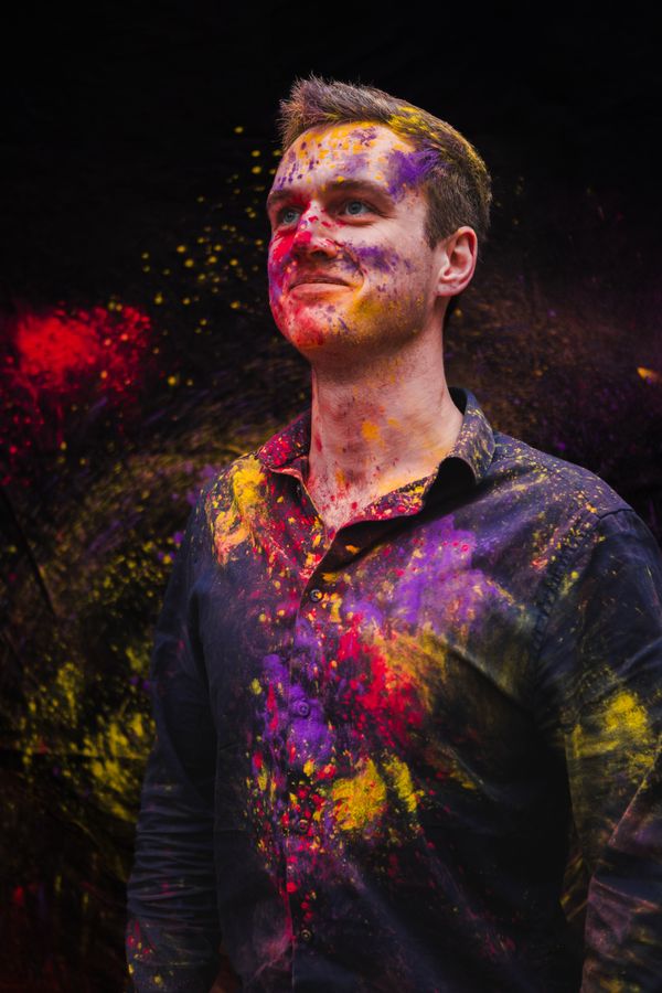 Mikey, mit bunten Holi-Farben bestäubt, blickt lächelnd nach oben